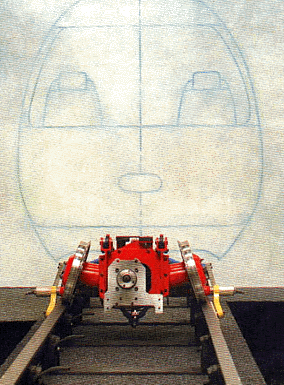 Photograph of the completed self-steering bogie hardware, red-painted, in front of a vehicle shell mock-up